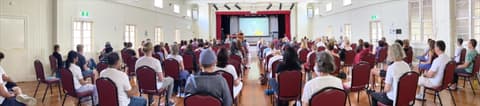 A full hall of people meditating together