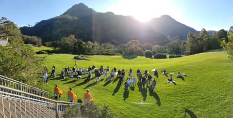 Meditating on a sunlit lawn below the mountains, guided by three monks